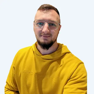 Łukasz Niesyto w okularach i żółtej bluzie.